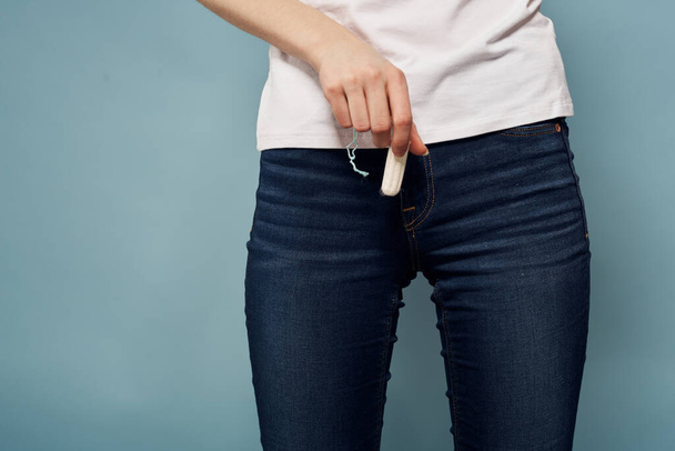 Woman with tampon and jeans t-shirt menstruation blue background cropped view hygiene - Foto, afbeelding
