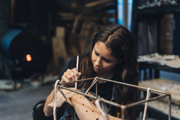 Portret van jonge vrouw genieten van favoriete baan in workshop. - Foto, afbeelding