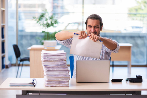 Jovem funcionário masculino infeliz com excesso de trabalho no escritório - Foto, Imagem