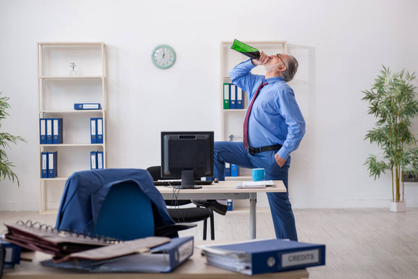 Старий працівник п'є алкоголь в офісі
 - Фото, зображення