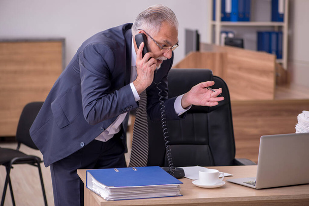 Old male employee unhappy with excessive work in the office - Photo, image