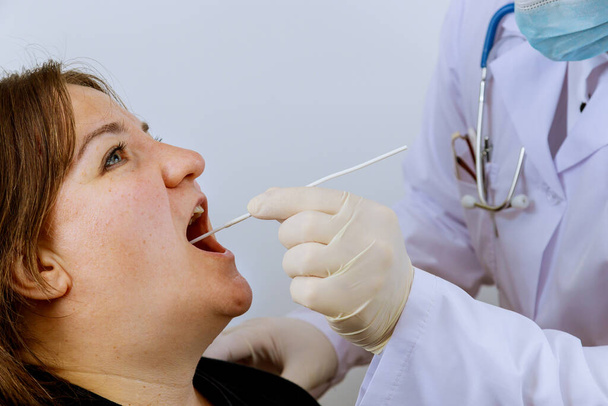 Covid-19 için PLR test koronavirüsü için ağız temizliği yapacak bir kadın doktor. - Fotoğraf, Görsel
