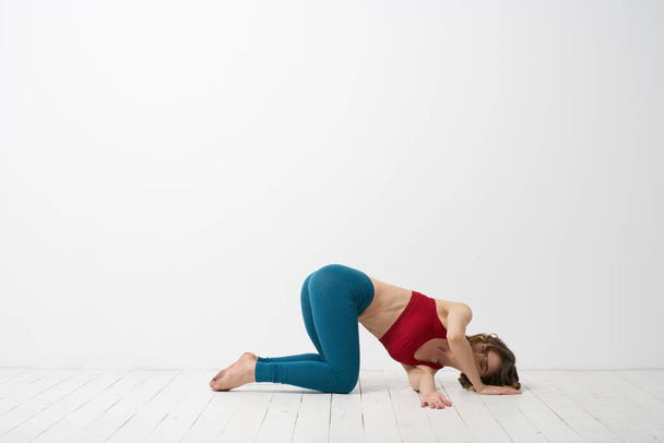 vrouw in leggings is bezig met gymnastiek in een lichte kamer slanke figuur fitness sport - Foto, afbeelding