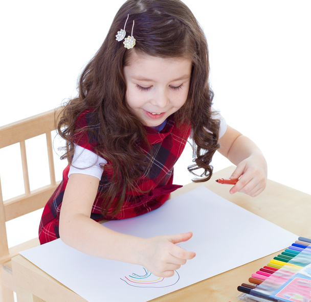 Little girl is drawing using color pencils while sitting at tabl - Zdjęcie, obraz