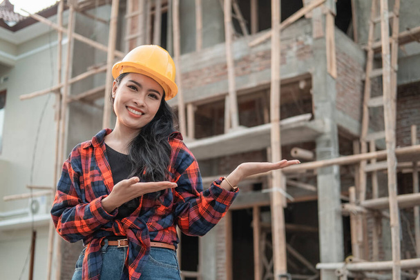 beautiful female contractors with gestures offer something wearing a safety helmet - 写真・画像