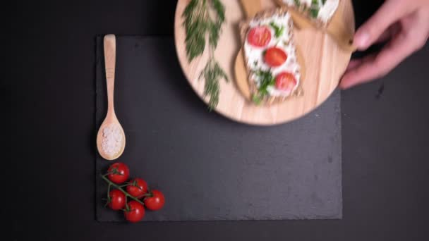 knäckebröd met roomkaas kerstomaten peterselie en zeezout op een glanzende zwarte achtergrond. vlakke lay - Video