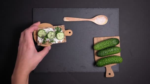 knapperig brood met verse komkommer met dille en roomkaas, rustieke biologische gezonde sandwich. Vlakke wip. verticale video - Video