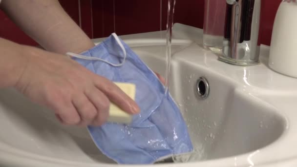 流しの中で医療マスクを洗う。綿はCovid-19から保護するための再利用可能な医療用マスク. - 映像、動画