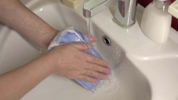 Orvosi maszkot mosok a mosogatóban. Pamut újrafelhasználható orvosi maszk a Covid-19 elleni védelemhez. - Felvétel, videó