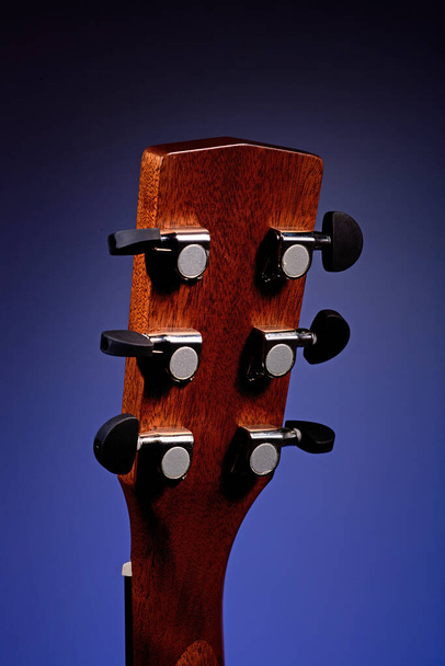 Akoestische gitaar hals met snaren close-up. Een achtergrond voor bijles geven en leren gitaar spelen. Muziekinstrument op een gekleurde achtergrond. Mockup - Foto, afbeelding