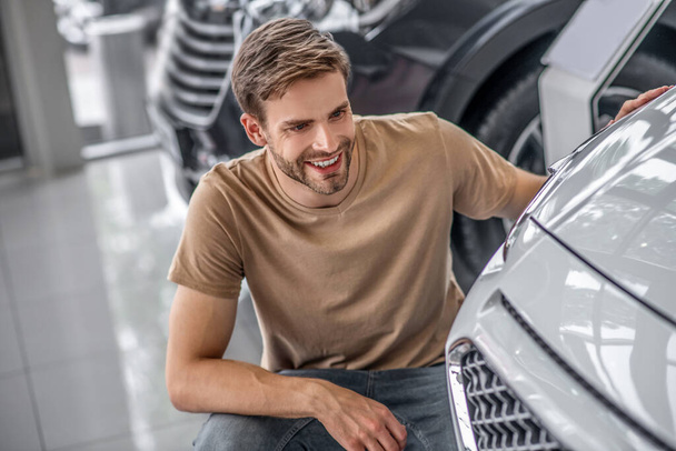 Excited male customer crouching examining car front lights - Foto, imagen