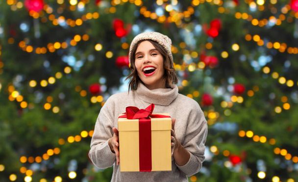 happy young woman in hat holding chrismas gift - Foto, afbeelding