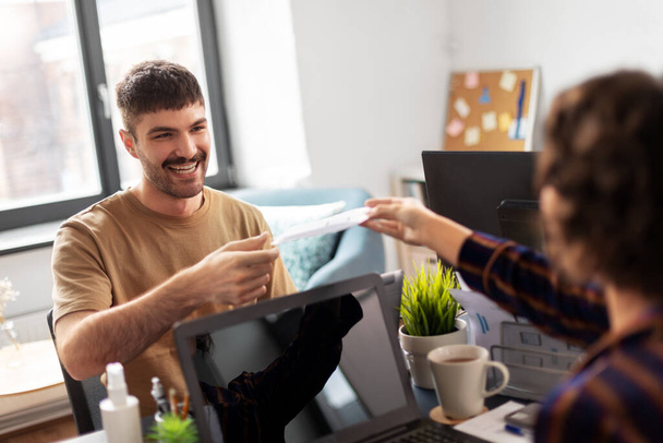 smiling man taking papers from colleague at office - Photo, Image