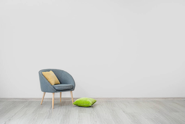 Стильное кресло с подушками возле светлой стены в номере - Фото, изображение
