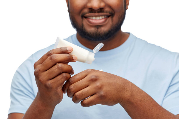 happy african man applying moisturizer to his hand - Foto, imagen
