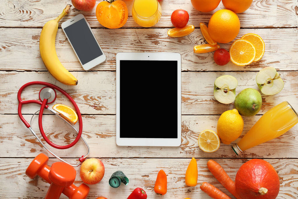 Fresh products, tablet computer, mobile phone and stethoscope on white wooden background. Diet concept - Photo, Image