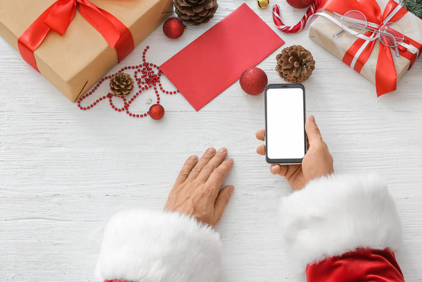 Père Noël avec téléphone portable à table - Photo, image