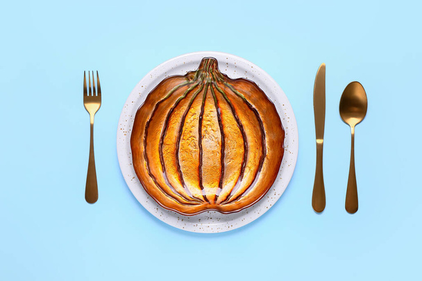 Beautiful plate in shape of pumpkin and cutlery on color background - Photo, Image