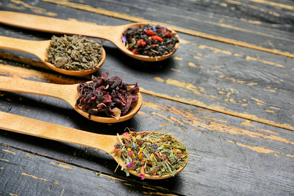 Colheres com diferentes tipos de chá de frutas em fundo de madeira escura - Foto, Imagem