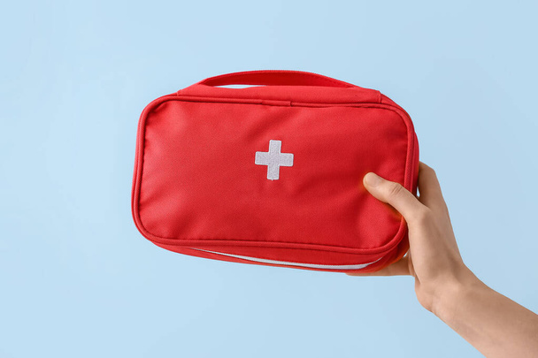 Hand with first aid kit on color background - Fotoğraf, Görsel