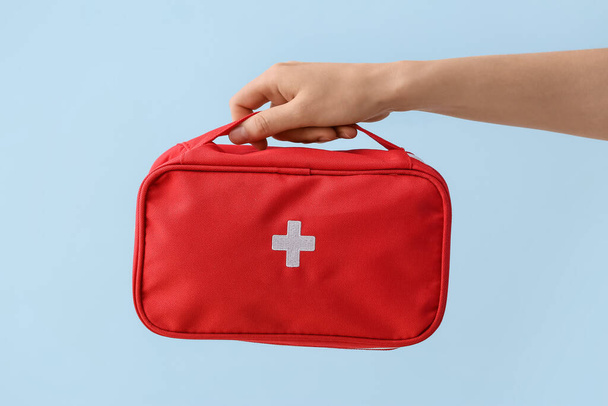 Hand with first aid kit on color background - Photo, Image