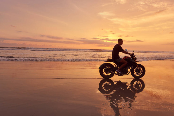 Man And Motorcycle On Ocean Beach At Beautiful Tropical Sunset. Handsome Biker On Motorbike On Sandy Coast In Bali, Indonesia. - Foto, imagen