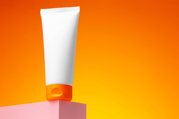 Blank white cosmetic container against orange background - 写真・画像
