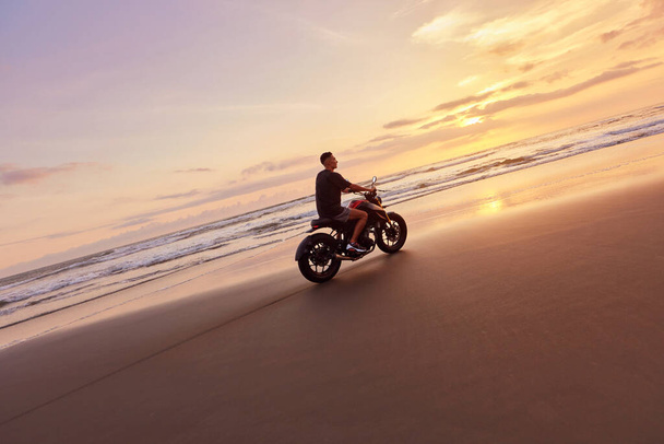 Man And Motorcycle On Ocean Beach At Beautiful Tropical Sunset. Biker Silhouette On Motorbike On Sandy Coast Near Sea In Bali, Indonesia. - Фото, изображение