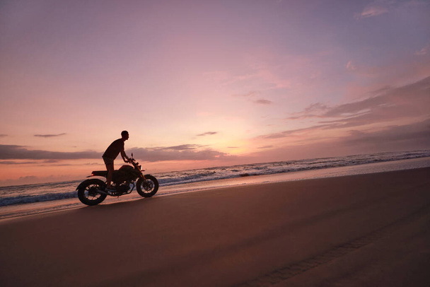 Man And Motorcycle On Ocean Beach At Beautiful Tropical Sunset. Biker Silhouette On Motorbike On Sandy Coast Near Sea In Bali, Indonesia. - Zdjęcie, obraz