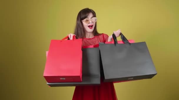 Happy young woman with shopping bags on color background. Black Friday sale - Кадры, видео