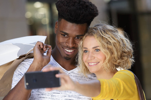 attractive young couple with shopping bags taking a selfie - Foto, immagini