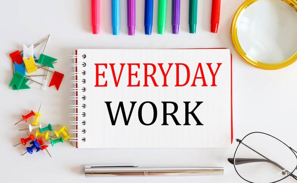 Notebook with EVERYDAY WORK word with office tools on white table. - Zdjęcie, obraz