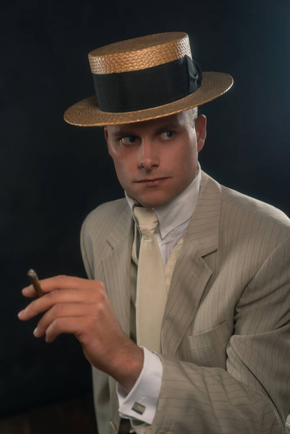 Man wearing boater hat and suit smoking cigar. - Foto, imagen