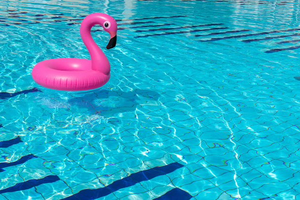 Zomer concept achtergrond. Roze opblaasbare flamingo in zwembadwater voor zomerse strand achtergrond. Zwembad float party. - Foto, afbeelding
