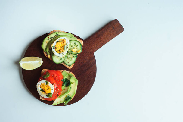 здоровый вегетарианский завтрак, тосты с авокадо с огурцом, яйца, помидоры и зеленый салат на цельнозерновом хлебе - Фото, изображение