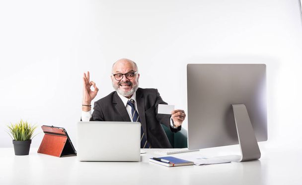Asiatischer Finanzunternehmer sitzt an seinem Arbeitsplatz oder Schreibtisch vor Computer, Laptop und Tablet. Telefonieren beim Papierkrieg - Foto, Bild