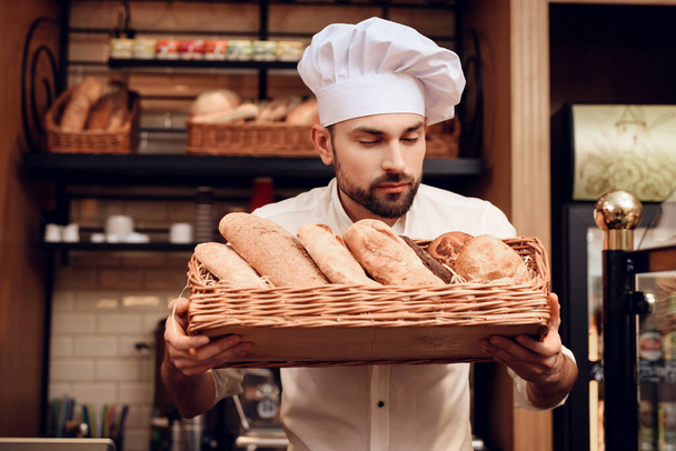 白い帽子の若い髭の男がパン屋に立っている. - 写真・画像