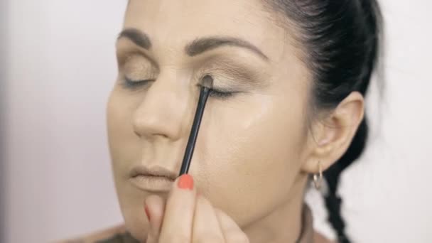 Maquillaje artista aplicando sombra de ojos para sí misma - Metraje, vídeo