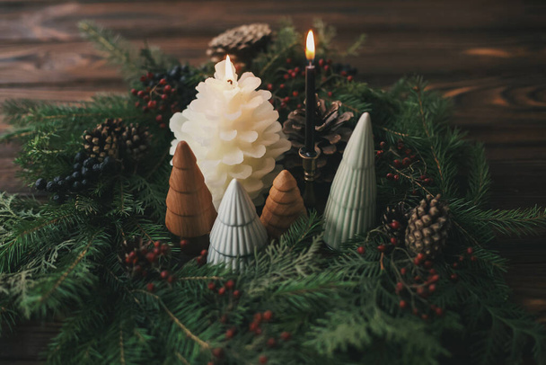 Decoración de la mesa de Navidad, corona moderna hecha a mano, pequeños árboles de Navidad y velas en la mesa de madera rústica. Decoraciones elegantes festivas para la cena de vacaciones en casa. Feliz Navidad.! - Foto, imagen