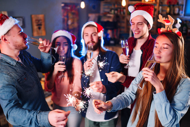 Group of happy friends celebrating  new year's party.  A crowd of young  people with sparklers, gifts and clinking glass. Party, holidays,  nightlife, holidays. Christmas. - Foto, afbeelding
