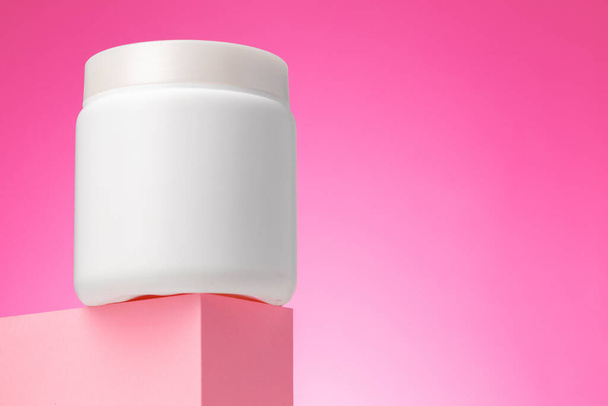 Blank white cosmetic container against pink background - Fotó, kép