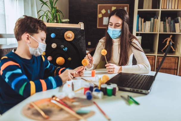 Щасливий школяр і дівчинка з захисною маскою роблять сонячну систему для шкільного наукового проекту вдома
 - Фото, зображення