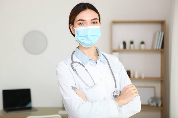 νεαρή κοπέλα γιατρός σε μια ιατρική μάσκα στο εσωτερικό του γραφείου - Φωτογραφία, εικόνα