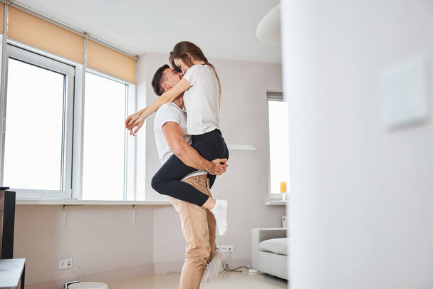 Excited gentleman and his girlfriend hugging at home - 写真・画像