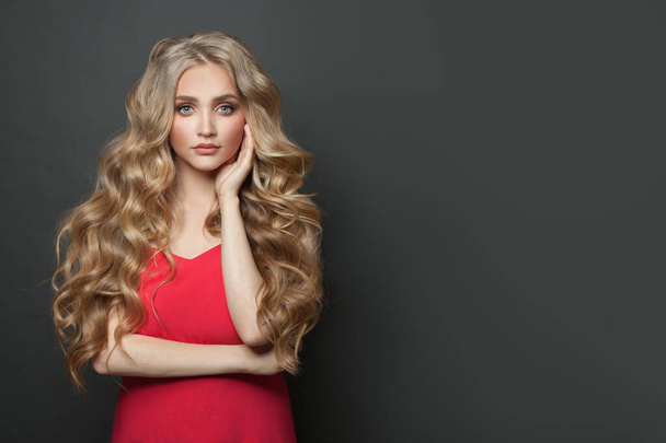 Hezká žena celebrity s make-upem a blondýny kudrnatý účes v červených večerních šatech na černém pozadí - Fotografie, Obrázek