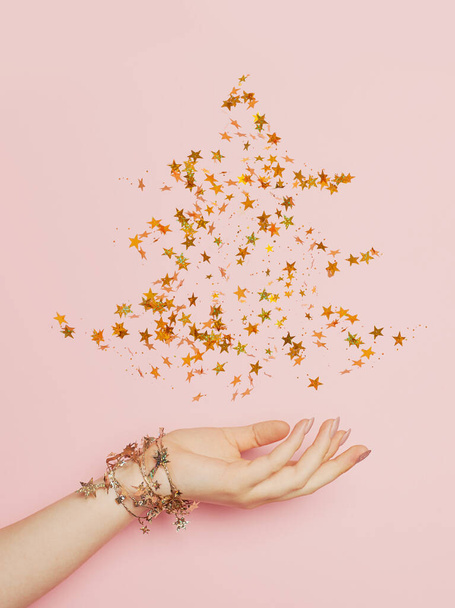 Christmas tree made from golden confetty stars on pink background. Minimal Christmas card - Valokuva, kuva