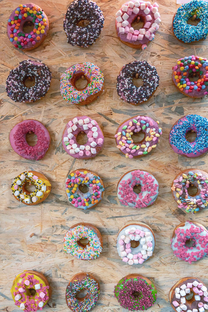 Kaksikymmentäkolme donitseja eri täytettä eri värejä ja makuja puulaudalla - Valokuva, kuva