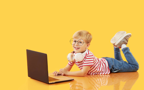 Litttle child boy using laptop on yellow background. Education, online study, home studying, distance learning. Primary school student during quarantine - Foto, Imagem