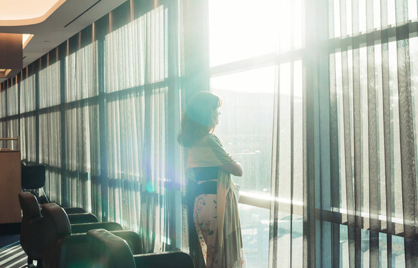 Woman looking through the window in airport terminal - Foto, afbeelding