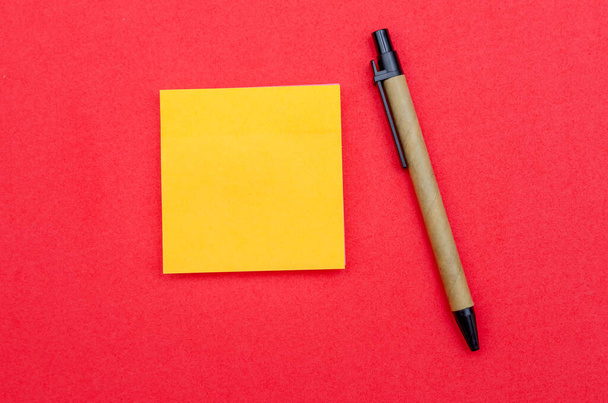 黄色い紙、赤い背景のボールペン、コピースペース、トップビュー - 写真・画像